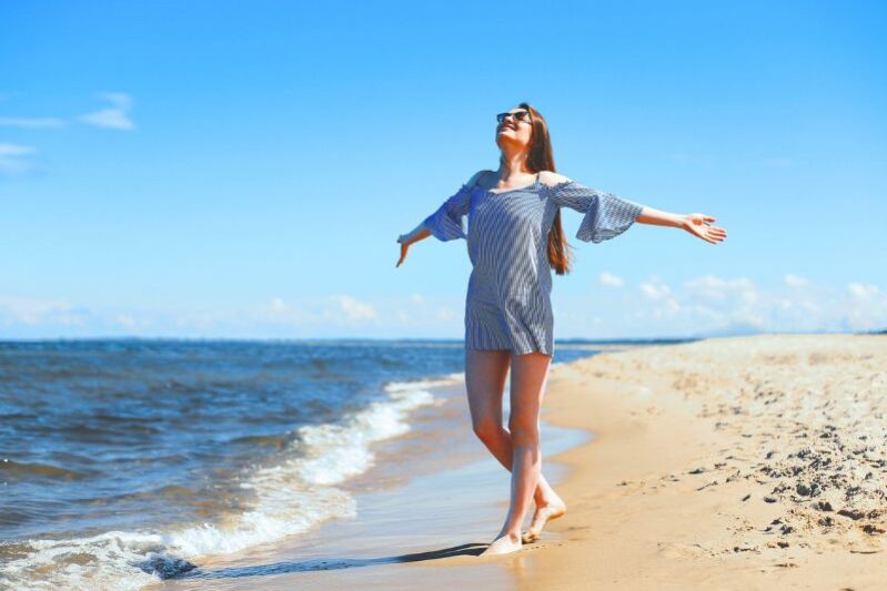 Woman with outstretched arms enjoying a day on the beautiful beach